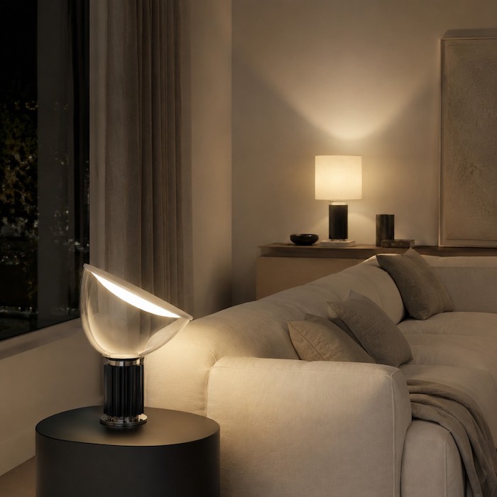 Black glass bowl lamp in a dark room balanced by warm-grey textiles and soft background light