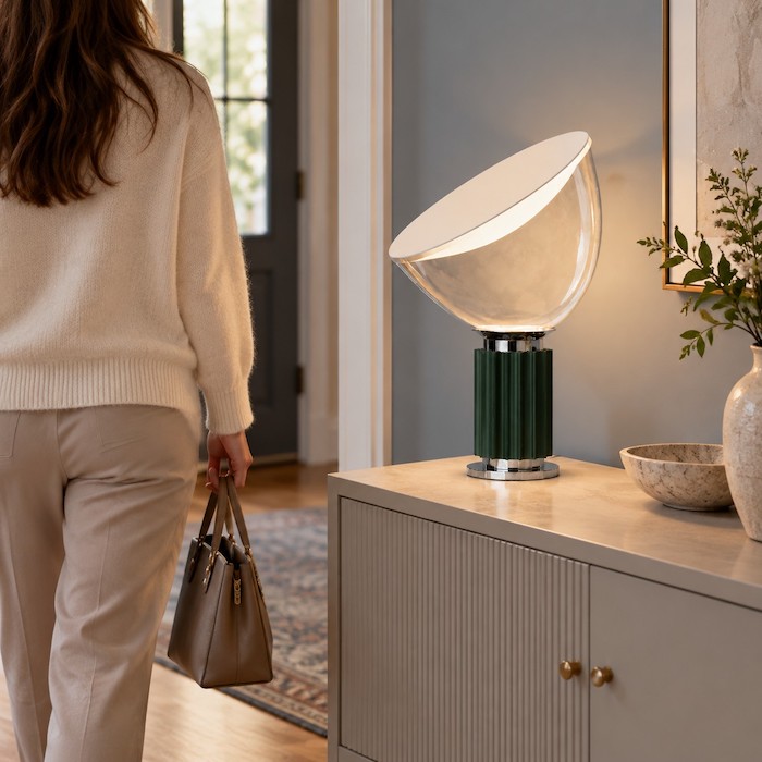 Person walking past a glass bowl lamp on a console while carrying a bag