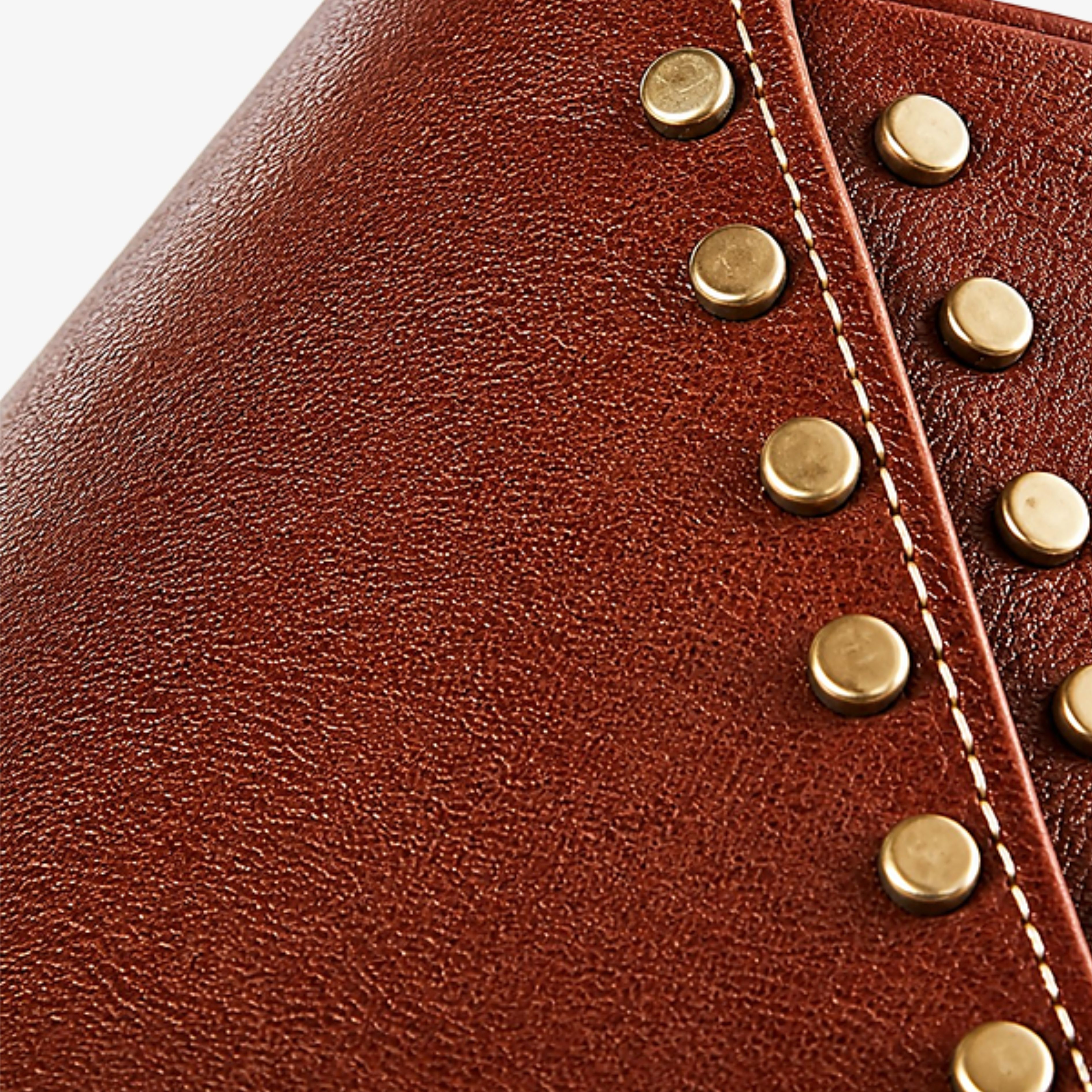 Hand-finished leather seam with antique brass rivets