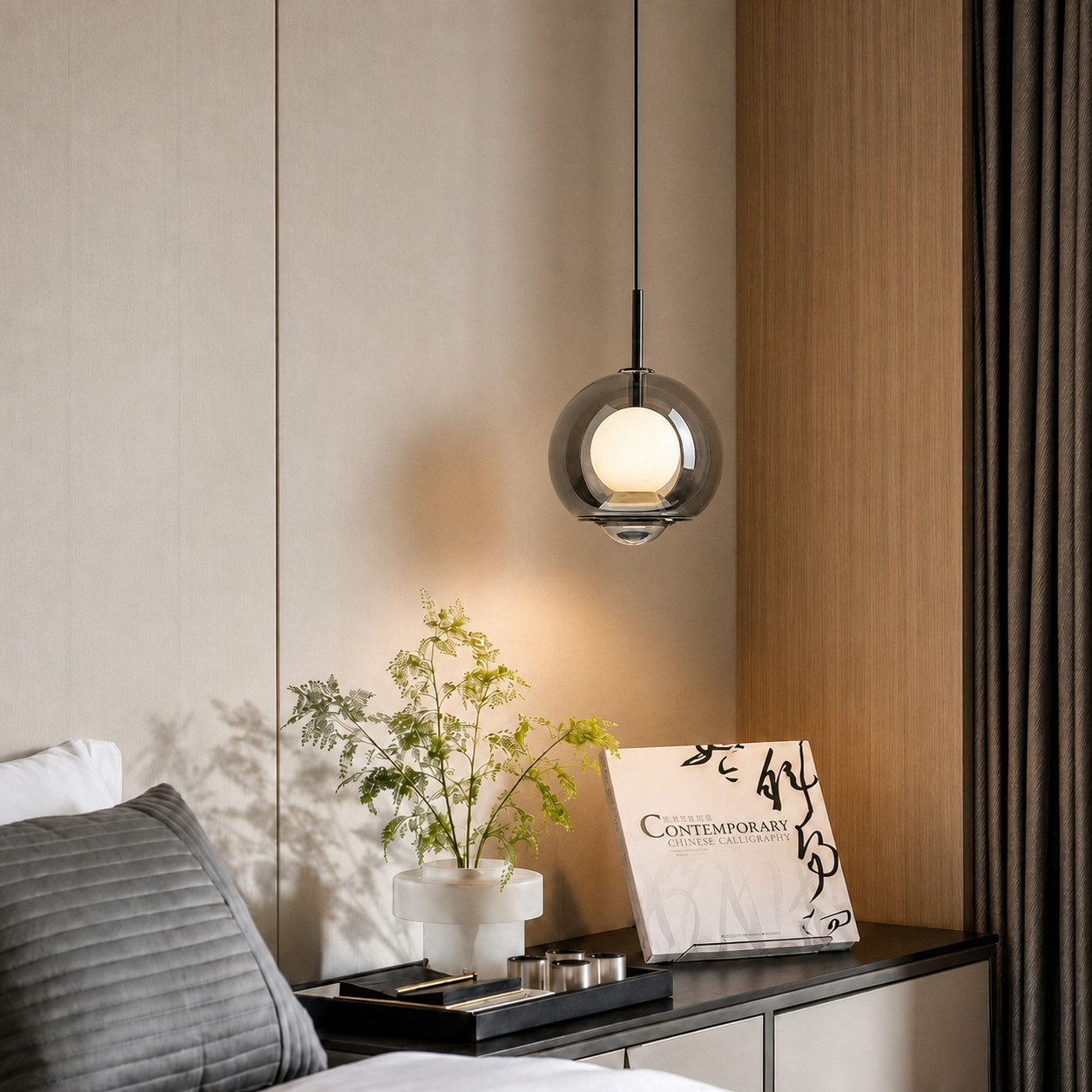 Smoked double-globe pendant above a bedside cabinet