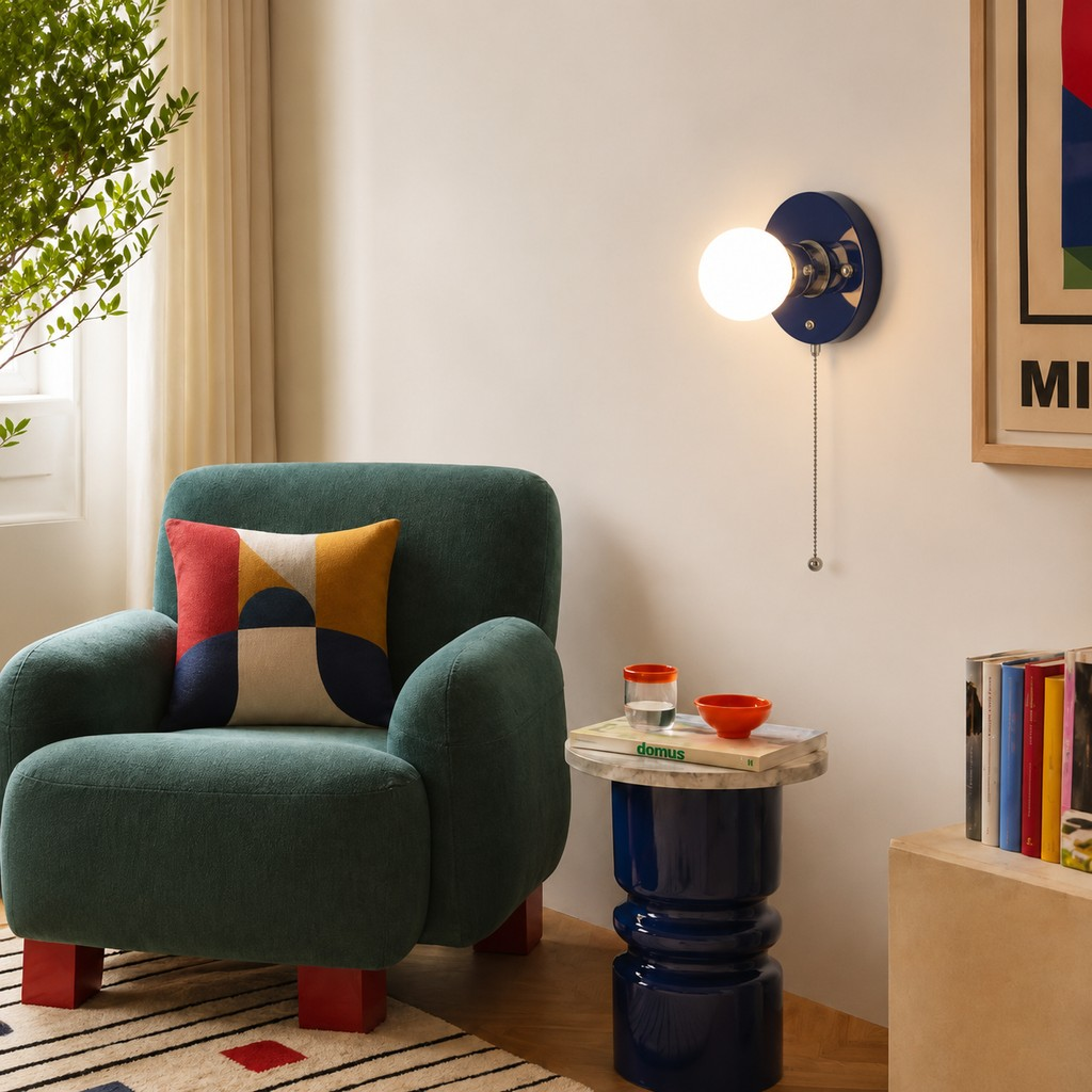 Navy blue pull-chain wall lamp beside a reading chair