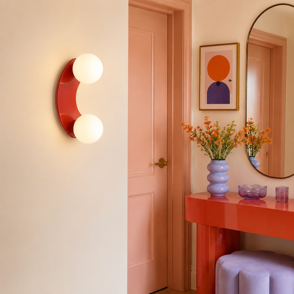 Terracotta double-globe wall lamp beside a coral console