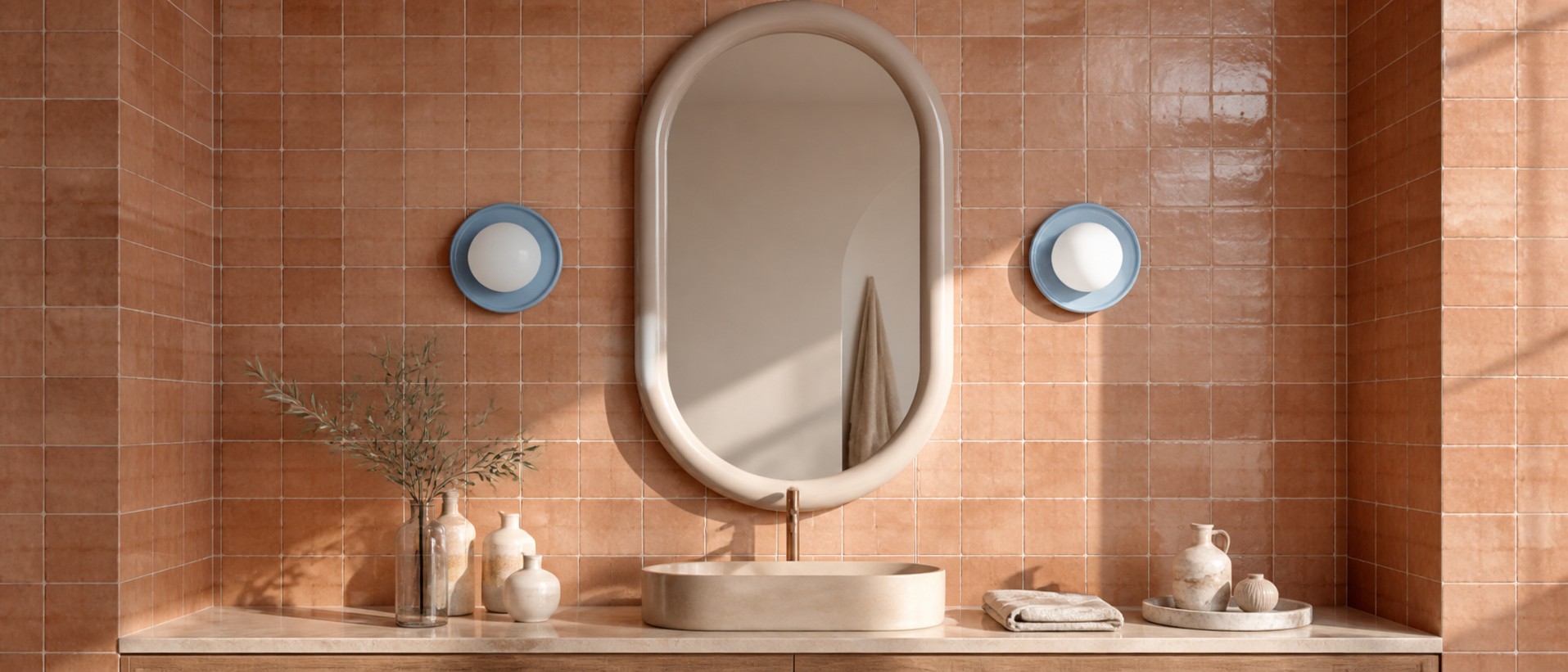 Blue globe wall sconces framing an arched mirror in a terracotta tiled bathroom