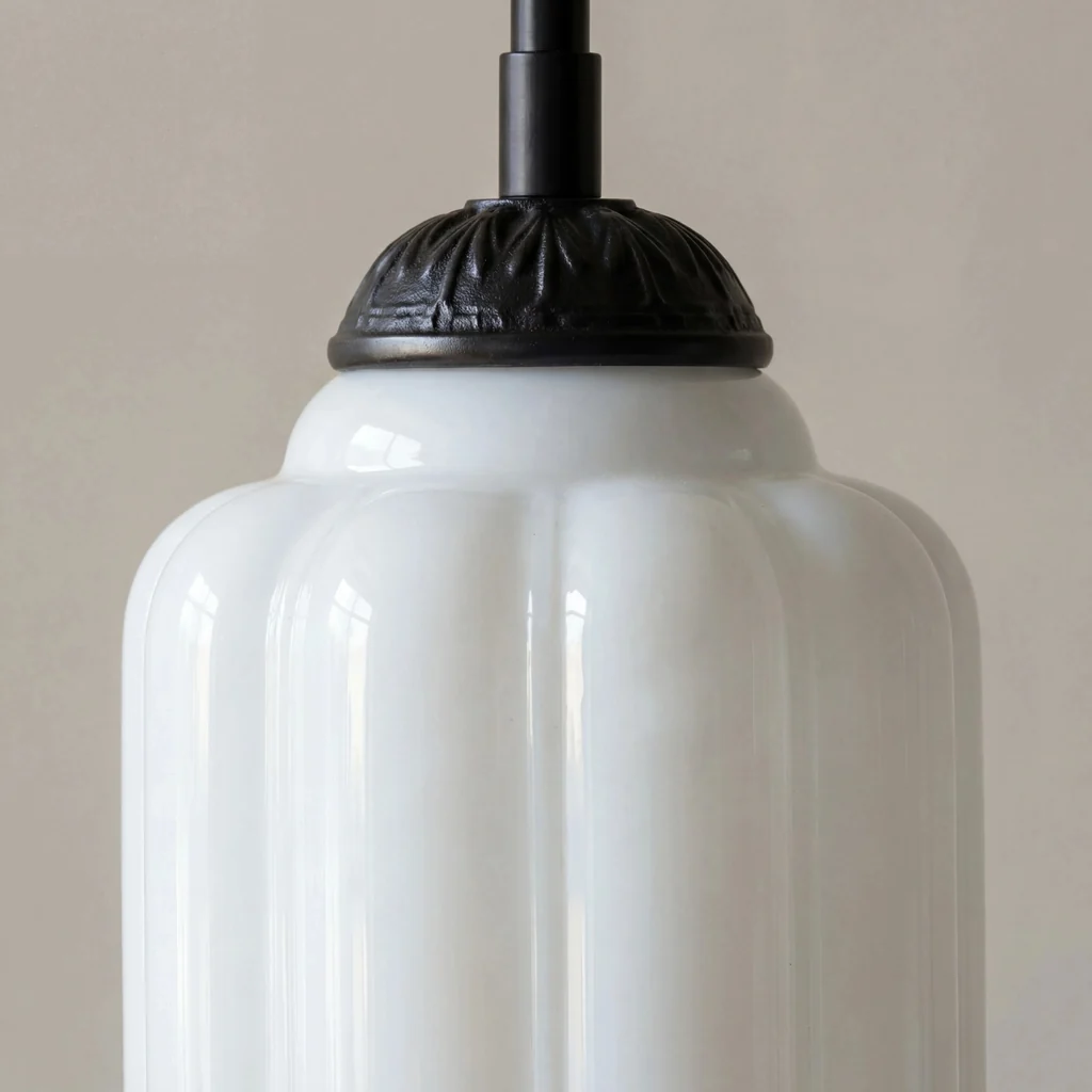 Ornate dark metal cap and suspension rod on white glass