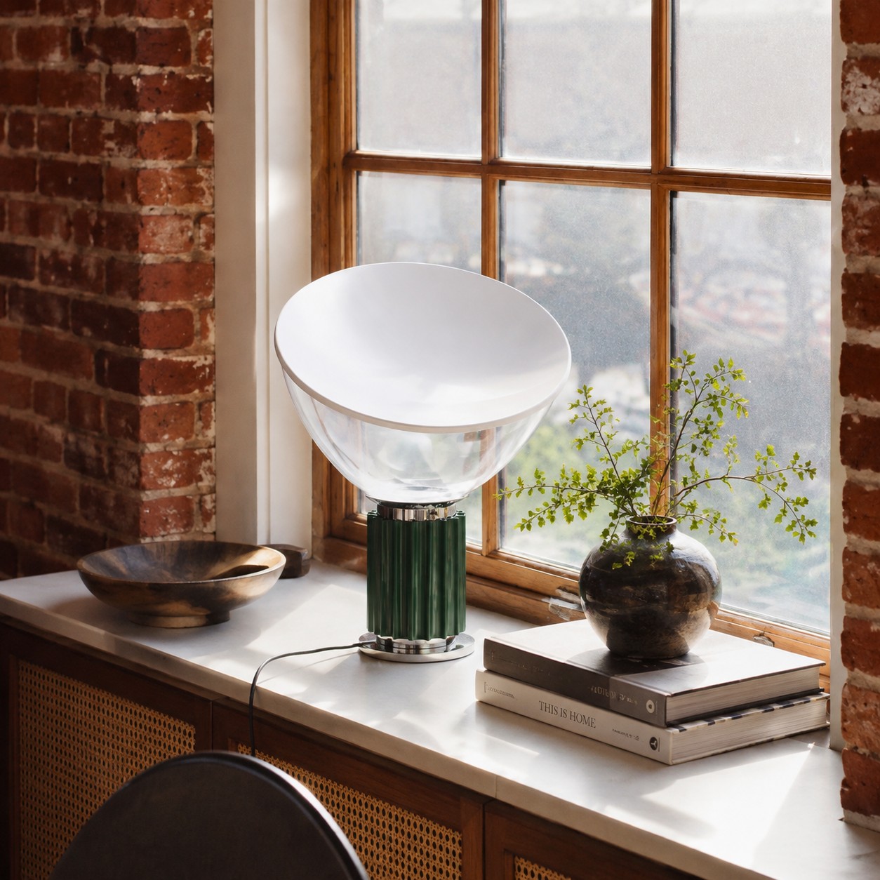 Deep green Taccia lamp on a sunlit windowsill