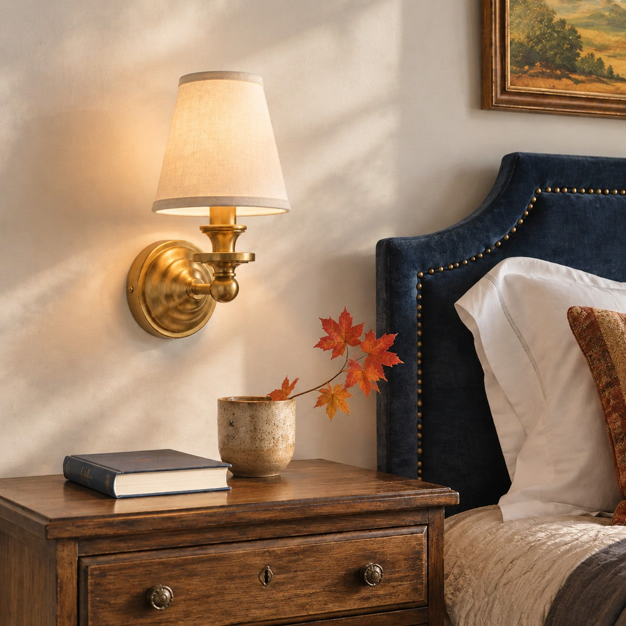 Brass Kalvora wall sconce over a wooden nightstand