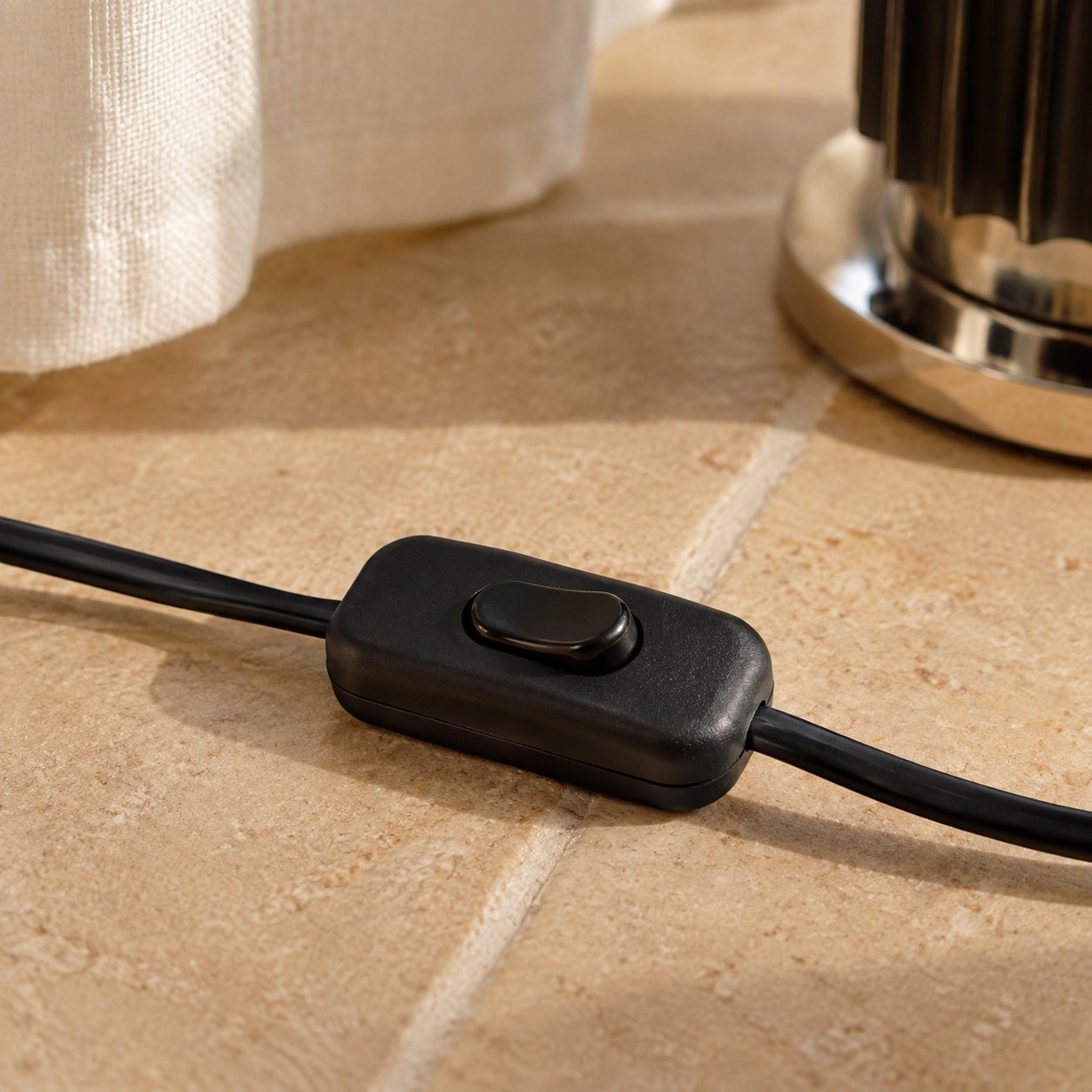 Primer plano del interruptor basculante negro de encendido y apagado en el cable de la lámpara de mesa Taccia