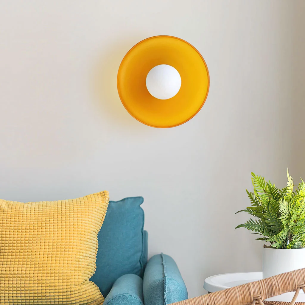 Yellow glass disc wall sconce above a sofa
