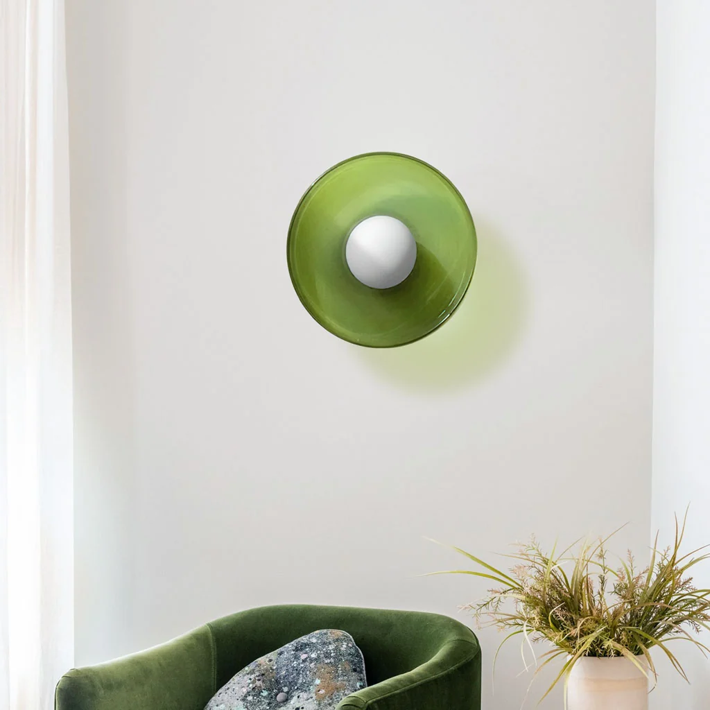 Green glass disc wall sconce above a chair