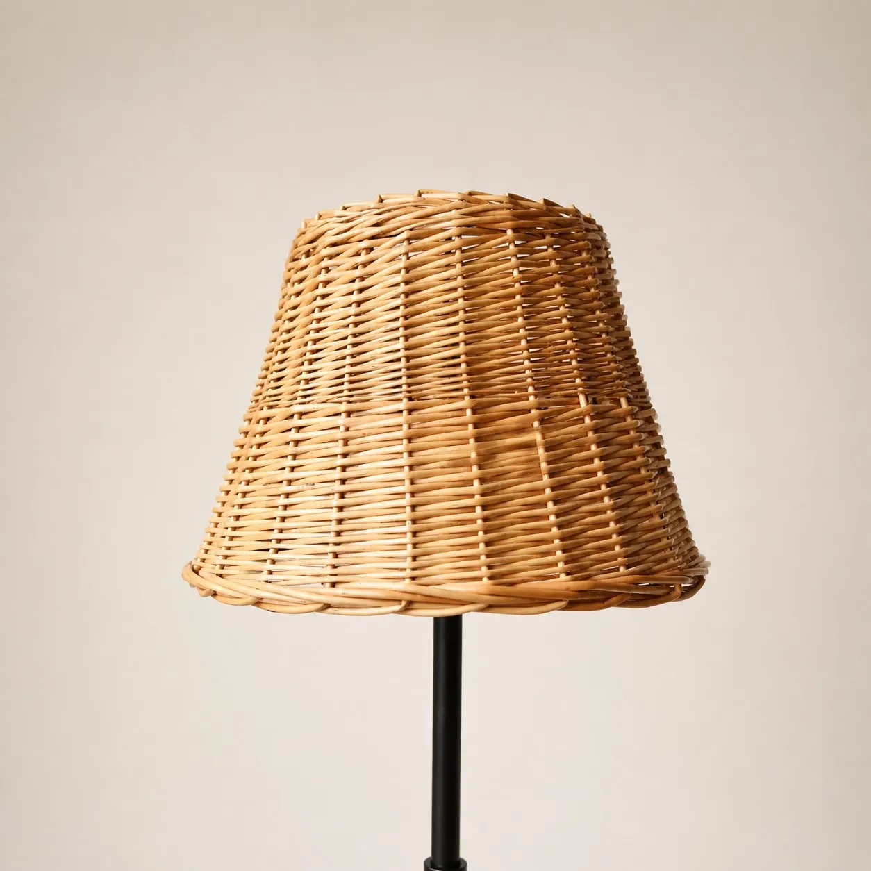 Rattan lampshade on slim black floor lamp stand