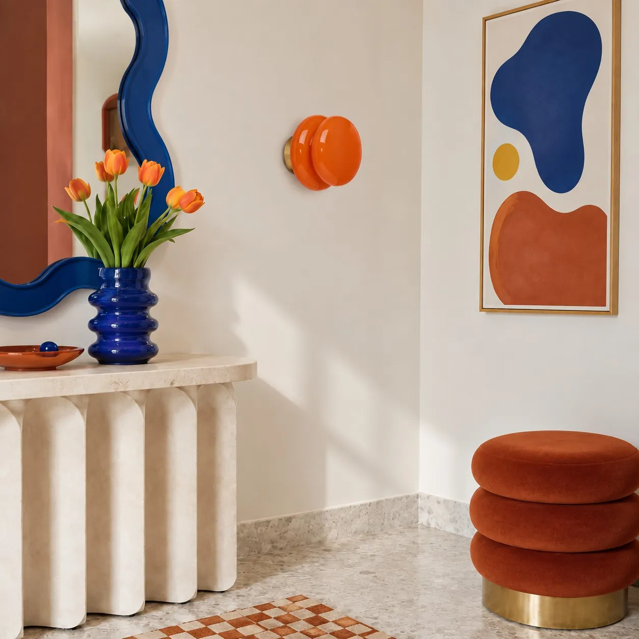 Pyris orange wall light beside a sculptural blue mirror