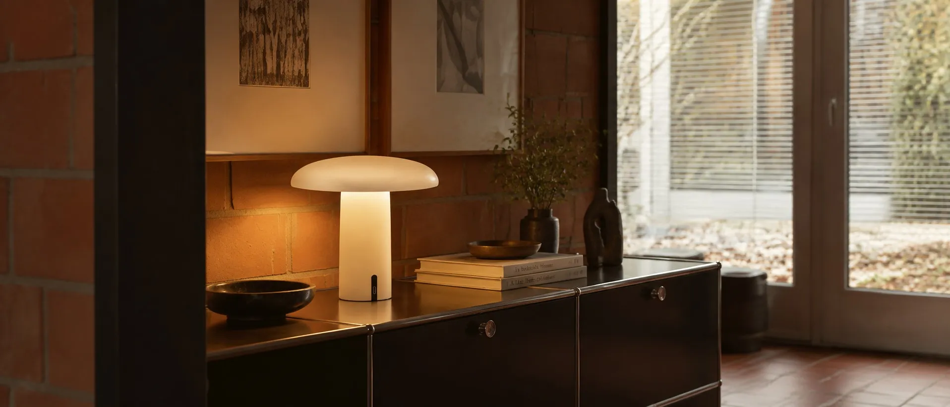 Takku portable table lamp glowing on a sideboard in a warm interior