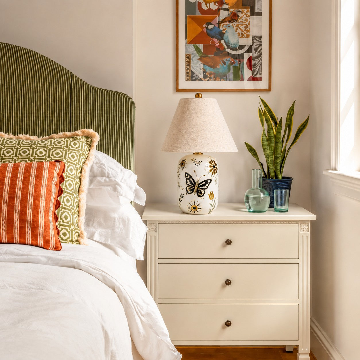 Neutral tapered linen shade table lamp beside a bed